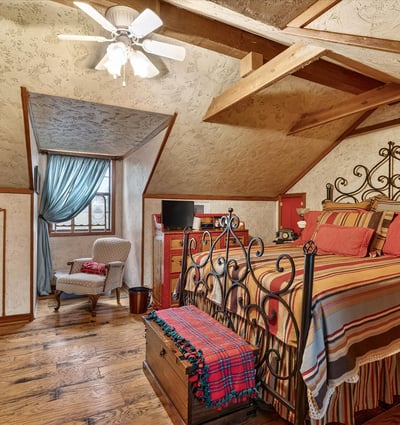 Cozy loft bedroom featuring exposed beams, a unique design, and ample natural light from large windows.