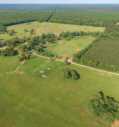 Expansive rural landscape featuring open fields, mixed woodlands, and potential for agricultural or recreational use.