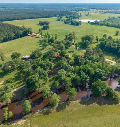 Expansive rural property with lush greenery, waterways, and multiple outbuildings, ideal for diverse development opportunities.