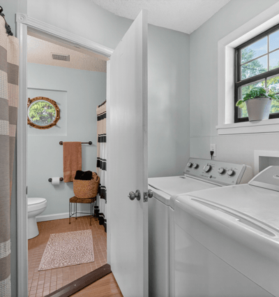 Bright and functional laundry area seamlessly connecting to a full bathroom.