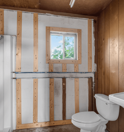 This unfinished bathroom features a shower area, sink, and window for natural light, ready for renovation.