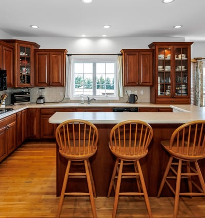 Highlights of the beautiful Kitchen include cherry cabinets, tile backsplash, Island with breakfast bar, hardwood flooring, and recessed lighting.