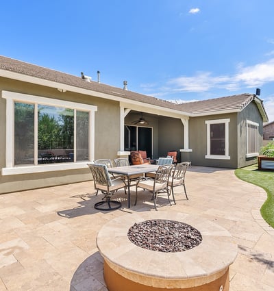This expansive paver backyard offers a perfect blend of function and fun with its built-in BBQ, firepit, and seating for gatherings under the Arizona sky.