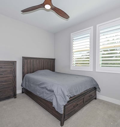 Plantation shutters, neutral paint, and plush carpet make this bedroom a perfect space for guests, an office, or a creative zone.