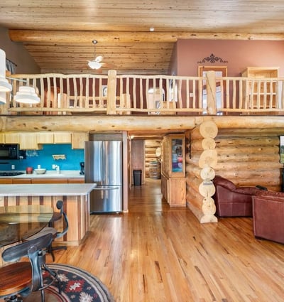 View of the kitchen opening into the living area, featuring stainless steel appliances, wood cabinetry, and seamless indoor flow for entertaining.