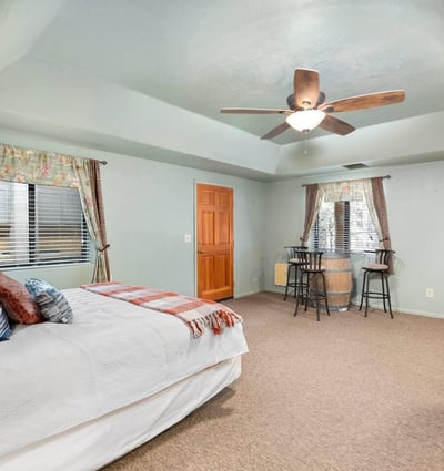 Private lower-level guest suite offering bedroom space, ceiling fan, and nearby kitchenette for extended stays or flexible living.