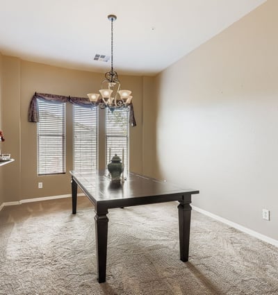 An elegant dining room with chandelier and oversized windows offers a welcoming space for hosting dinners and celebrations.