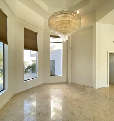 Elegant dining room featuring a stunning chandelier, soaring ceilings, and tall windows that fill the space with warmth and sophistication.