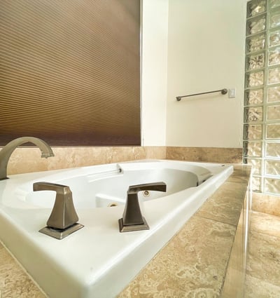 Luxurious soaking tub surrounded by elegant marble tile and designer fixtures, creating a tranquil retreat within this Scottsdale home.