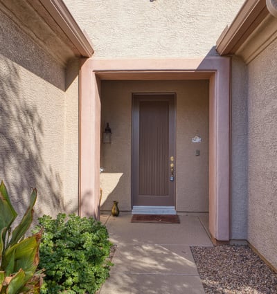A covered entry framed by natural desert tones offers a warm welcome. Thoughtfully designed for shade and comfort, this entrance sets the tone for a peaceful home experience.
