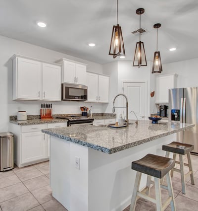 This modern kitchen highlights an oversized granite island, sleek pendant lights, stainless appliances, and energy-efficient lighting ideal for cooking and entertaining in Litchfield Park.