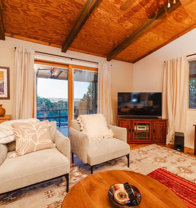 Featuring wood-accent ceilings and large windows, this cozy seating area delivers relaxing views of the deck and surrounding terrain. A welcoming space designed for comfort and connection to nature.