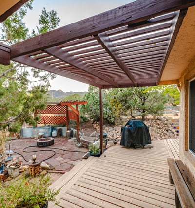 Featuring a shaded pergola, natural stonework, and mountain scenery, this outdoor patio is perfect for BBQs, lounging, and taking in the desert surroundings.