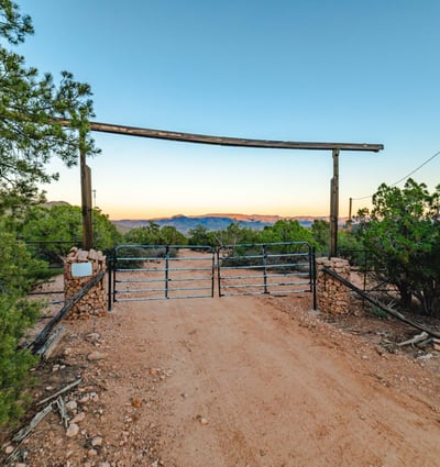 A classic double gate welcomes you to the property, framed by desert foliage and distant mountain ranges that accentuate its serene rural appeal.