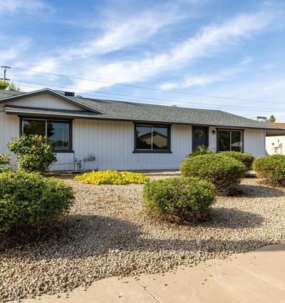 Easy-care desert landscaping with mature shrubs and a spacious driveway highlights the practical curb appeal of this well-maintained single-level Phoenix property.