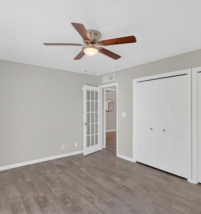 Well-sized bedroom with neutral tones, ceiling fan, and ample closet space, adaptable for guests or flexible living needs.