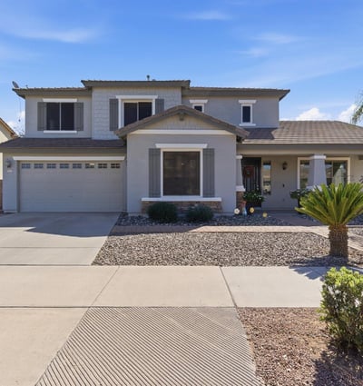 Attractive exterior of this Queen Creek property featuring a covered entry, desert landscaping, and attached garage in the popular Cortina community.
