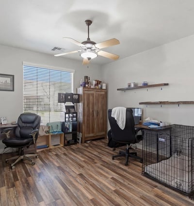 Spacious office area with wood-style flooring and large window, ideal for remote work, study, or a hobby room within this Queen Creek home.
