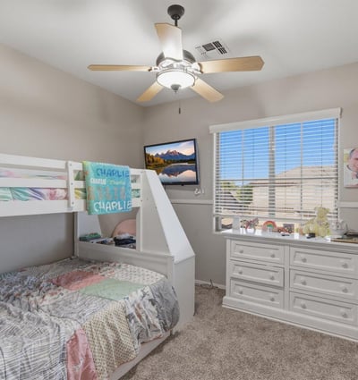 Cozy secondary bedroom with bunk bed arrangement, neutral paint, and large window allowing natural light into the room.