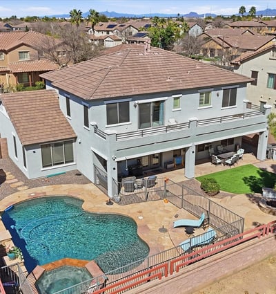 Drone perspective highlighting the backyard retreat with pool, spa, covered patio seating, and landscaped outdoor entertaining areas.