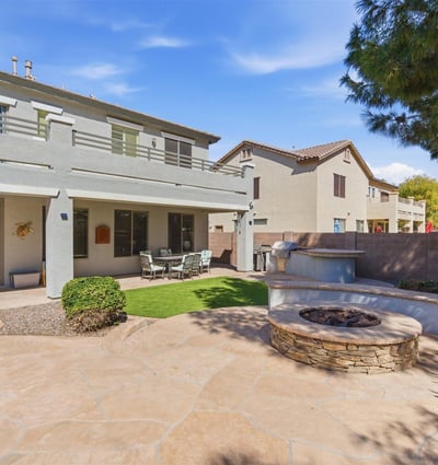 Backyard entertaining area featuring a built-in fire pit, spacious patio, and landscaped yard with pool views perfect for gatherings.