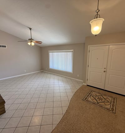 Spacious Glendale living room featuring tile flooring, neutral tones, vaulted ceilings, and a classic stone fireplace. The open design provides a comfortable gathering space with plenty of natural light.