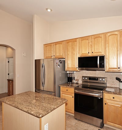 Kitchen with granite island, stainless appliances, and warm wood cabinetry. This Phoenix home provides functional prep space and a welcoming cooking area.