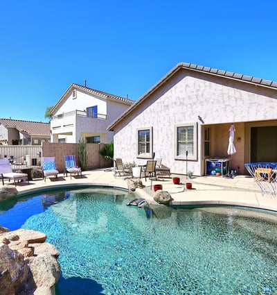 Backyard with Pebble Tec pool, rock waterfall feature, and spacious patio. This Phoenix home highlights outdoor living with low-maintenance desert landscaping.