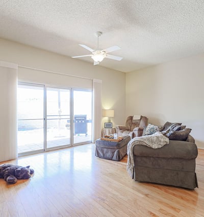 Open-concept living area with hardwood floors, ceiling fan, and large sliding doors leading to the backyard patio for indoor-outdoor living.