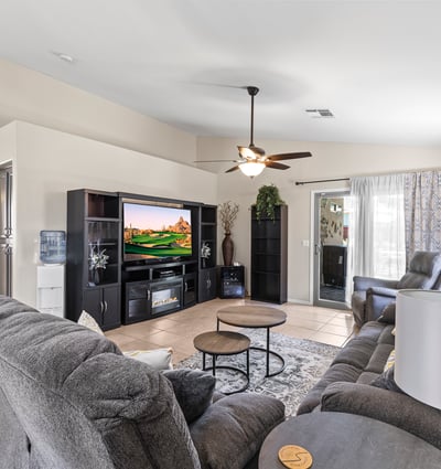 Comfortable family room with neutral finishes, ceiling fan, and open flow to kitchen and dining areas for easy living.