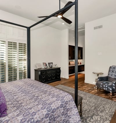 Inviting bedroom with ceiling fan, plantation shutters, and warm finishes, perfect for guests or additional living space in Phoenix.