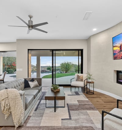 Open-concept living room with sleek fireplace, wood floors, and sliding doors leading to the backyard, showcasing Scottsdale indoor-outdoor design.