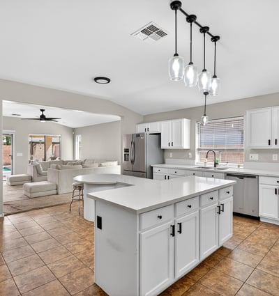 Spacious kitchen with large island, white cabinetry, and ample prep space. Open layout flows into living areas, making it ideal for gatherings in this Casa Grande property.