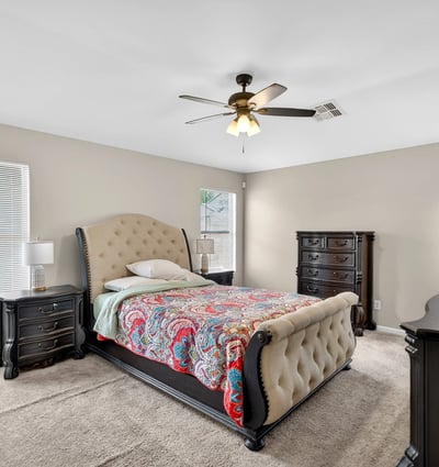 Generous primary bedroom with ceiling fan, soft carpet, and multiple windows. A relaxing retreat designed for comfort in this Casa Grande home.
