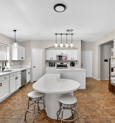 Functional kitchen with breakfast bar, white cabinets, and modern appliances. Seamless connection to living areas enhances flow in this Casa Grande home.