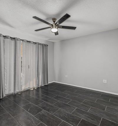 Bright bedroom with tile flooring, ceiling fan, and natural light. This Sun City home offers updated finishes and flexible room options.