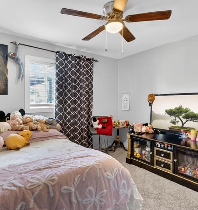 Cozy bedroom with plush carpeting, ceiling fan, and inviting layout, ideal for everyday comfort.
