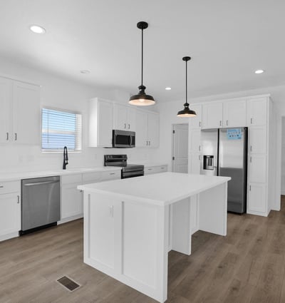 Modern kitchen with an oversized island, abundant cabinet storage, stainless steel appliances, and a walkthrough pantry. The clean design and generous workspace make meal preparation and entertaining effortless.