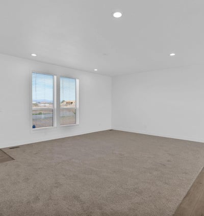 Welcoming front living room featuring soft carpeting, recessed lighting, and oversized windows. The spacious layout offers flexibility for entertaining guests, family activities, or creating a relaxing everyday living environment.