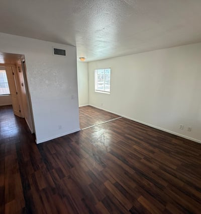 Large living room with rich wood-look flooring, neutral finishes, and a bright open feel. The spacious layout creates a welcoming environment ideal for entertaining guests or enjoying everyday comfort.