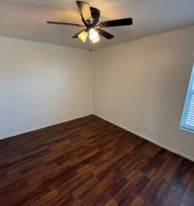 Bright and airy bedroom offering wood-look flooring, ceiling fan, and natural light. This versatile space works well as a guest room, home office, or primary sleeping area.
