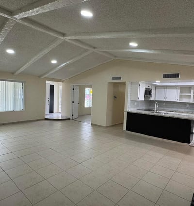 Light-filled great room seamlessly connected to the kitchen and surrounding living spaces. The vaulted ceiling design enhances openness and visual appeal throughout the home.