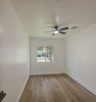 Relax in the spacious primary bedroom featuring updated flooring, modern ceiling fan, fresh interior finishes, and a bright, airy atmosphere in this Buckeye home.