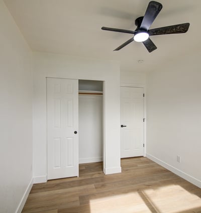 This inviting bedroom features updated flooring, fresh interior finishes, a ceiling fan, and a spacious closet, creating a comfortable space for guests, family members, or a home office.