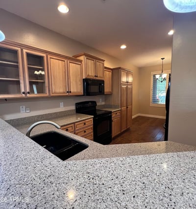 Spacious kitchen offering custom wood cabinetry, ample countertop space, breakfast bar seating, generous storage, and an open layout connecting seamlessly with the home's main living spaces.
