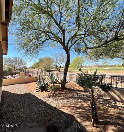 Backyard overlooking the fairway with mature desert trees, attractive landscaping, decorative stone accents, and scenic mountain views. This premium outdoor setting offers both privacy and breathtaking natural surroundings.
