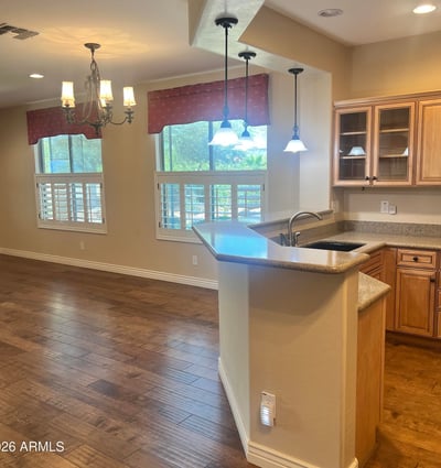 Inviting open-concept kitchen and dining area with custom cabinetry, breakfast bar, pendant lighting, plantation shutters, and upgraded flooring that creates a bright, welcoming atmosphere perfect for entertaining.