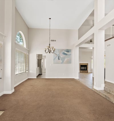 This generous living room offers soaring ceilings, oversized windows, and an open design that creates a bright, welcoming atmosphere. Perfect for everyday comfort or hosting family gatherings.