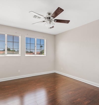 Rich wood flooring, large windows, ceiling fan, and neutral finishes make this spacious bedroom bright, comfortable, and move-in ready for family or guests.