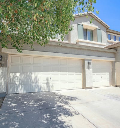 Charming front exterior showcasing a three-car garage, mature landscaping, and inviting covered entry. This attractive Waddell property offers excellent curb appeal and functional everyday convenience.
